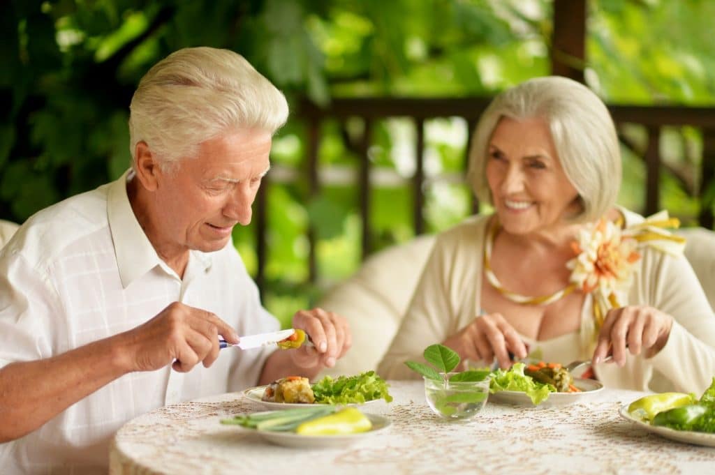 Couple senior partageant un repas en terrasse à Sorgues — accompagnement ARTEMIS